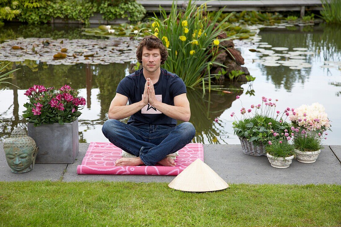 Mann meditiert im Garten