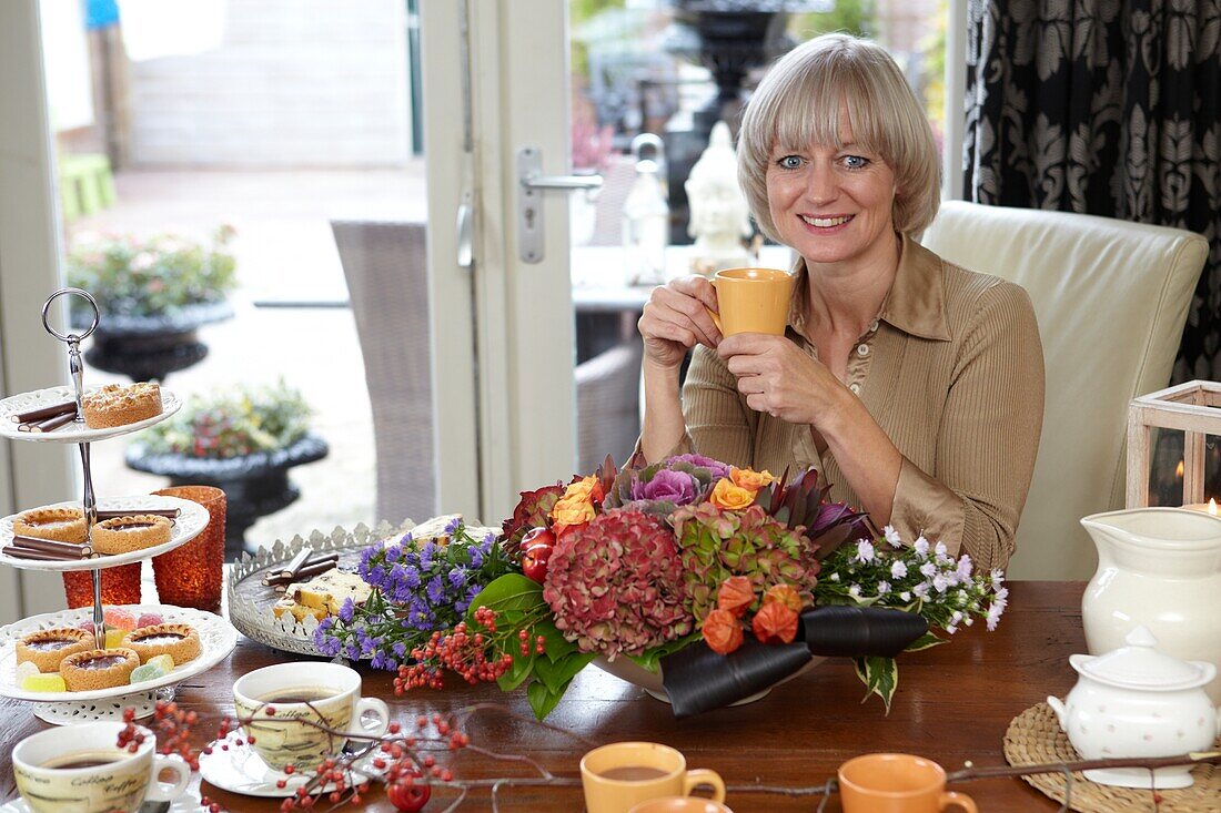 Florist sitzend bei Herbstgesteck