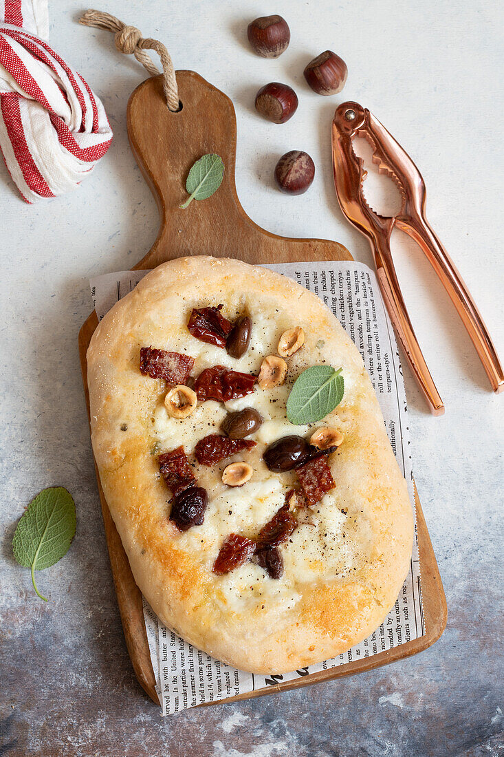 Pizza mit Mozzarella, getrockneten Tomaten und Haselnüssen