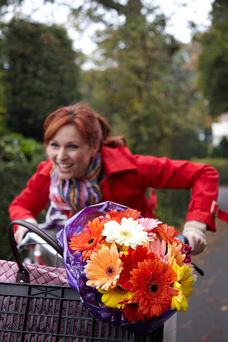 Woman riding bicycle holding flowers