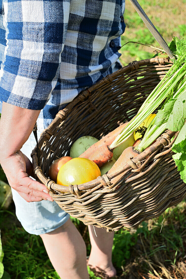Man carrying wicker basket with freshly harvested vegetables