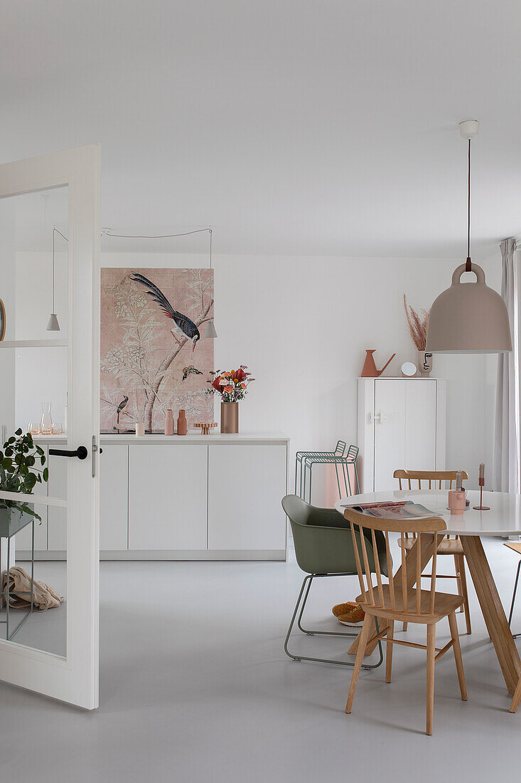 Bright dining room with wooden table, mixed chairs and bird mural