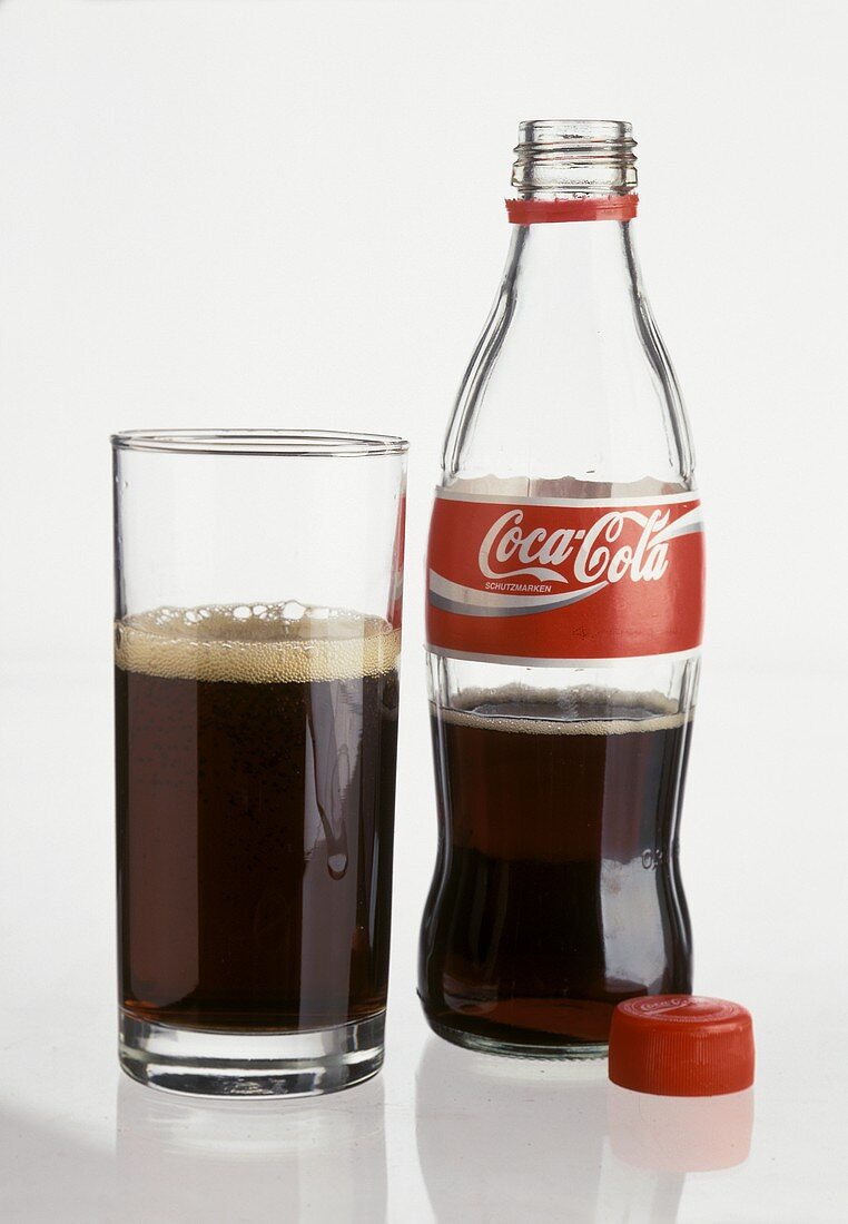 Small bottle of Coca Cola, opened & a glass of Cola