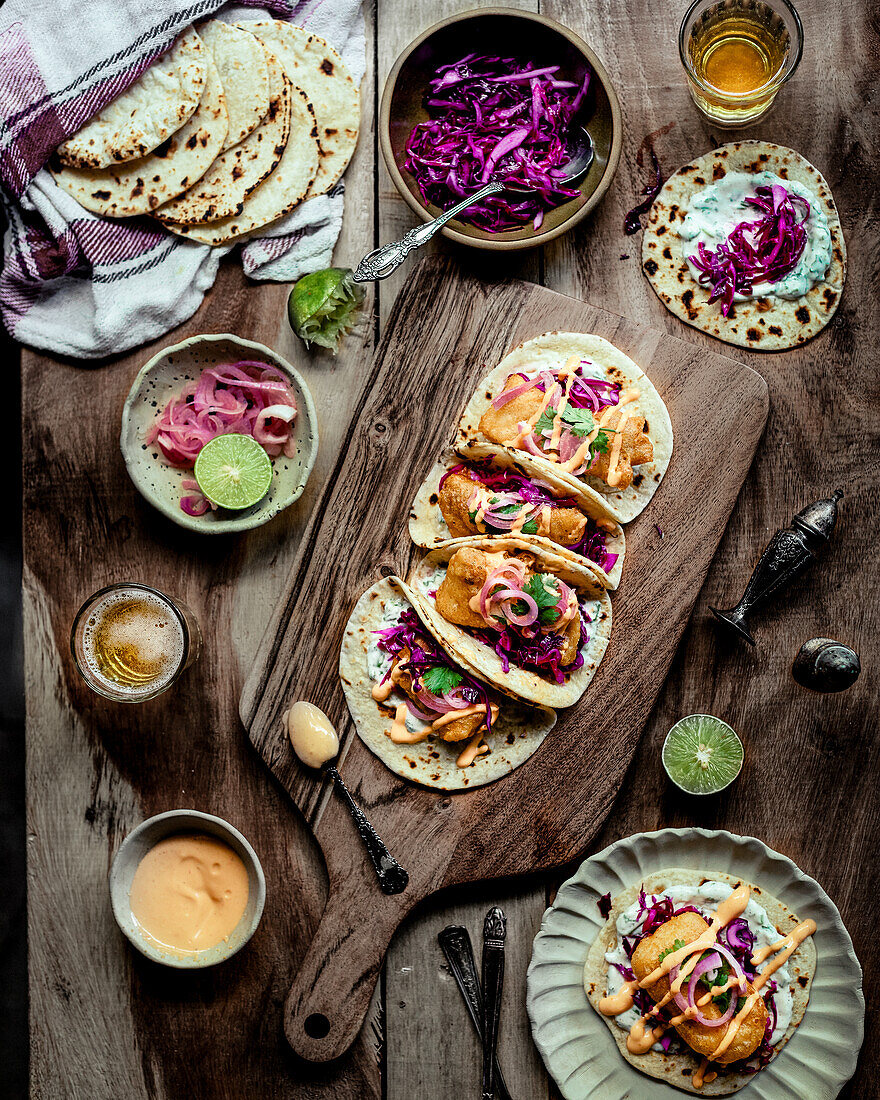 Tacos mit paniertem Fisch, Rotkohlsalat, eingelegten Zwiebeln und scharfer Sauce