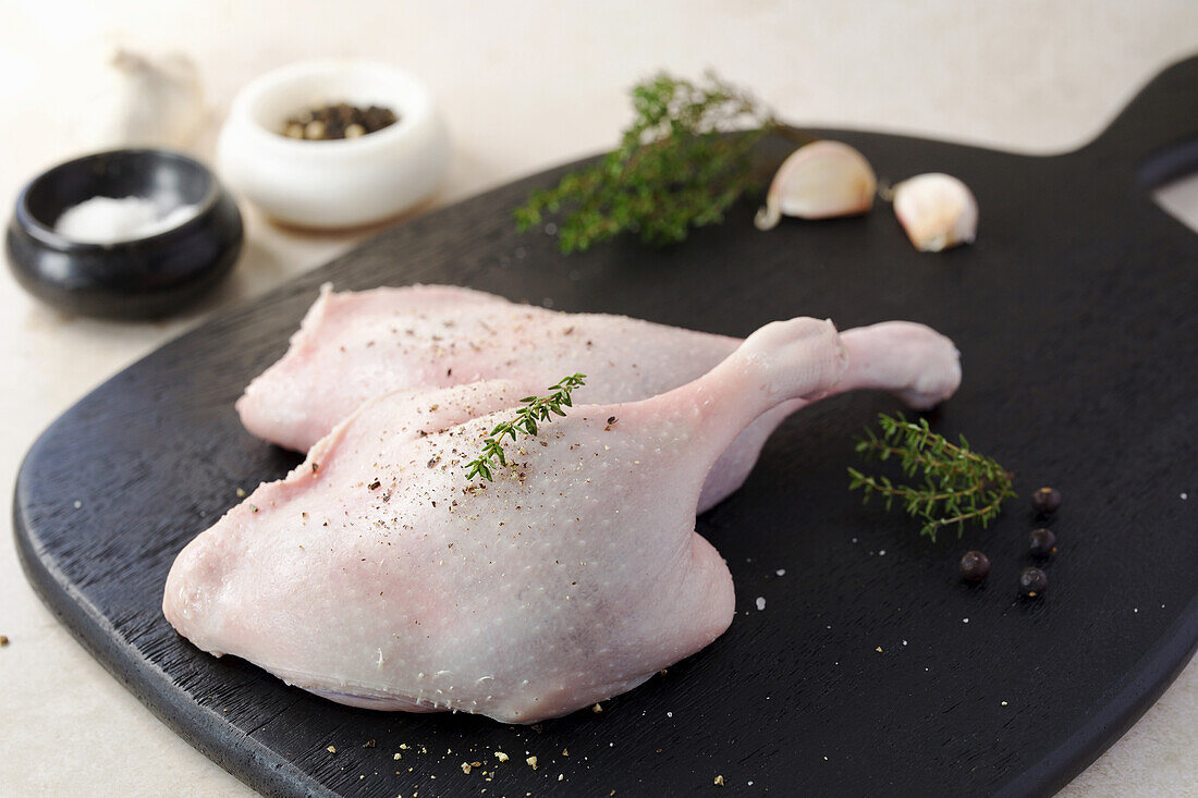 Two raw duck legs with herbs and spices