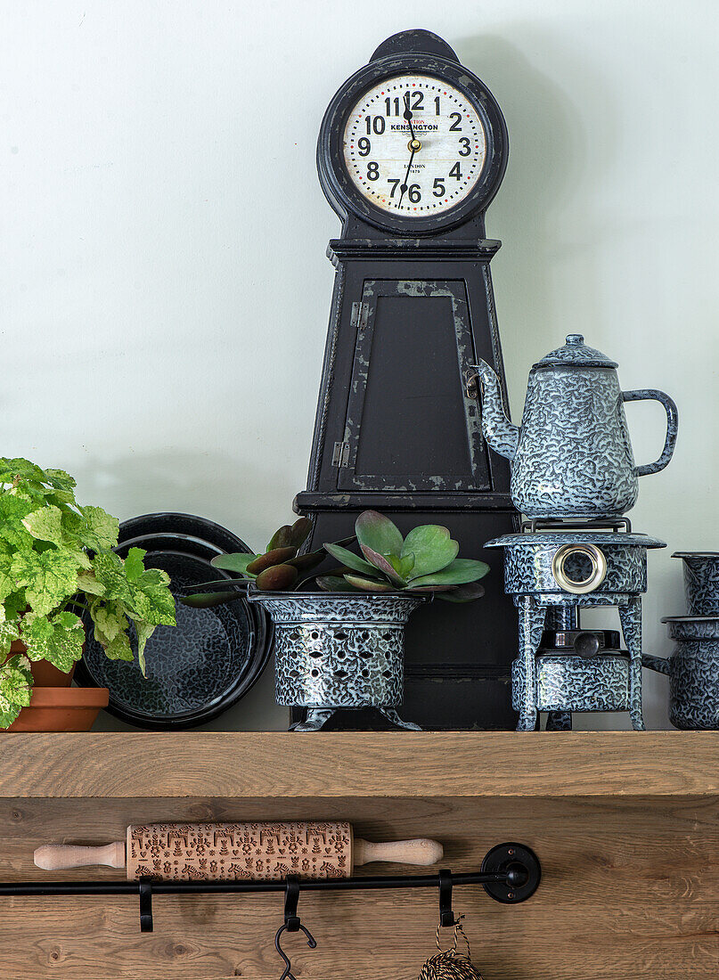 Vintage clock, pot with teapot and plants on a wooden shelf