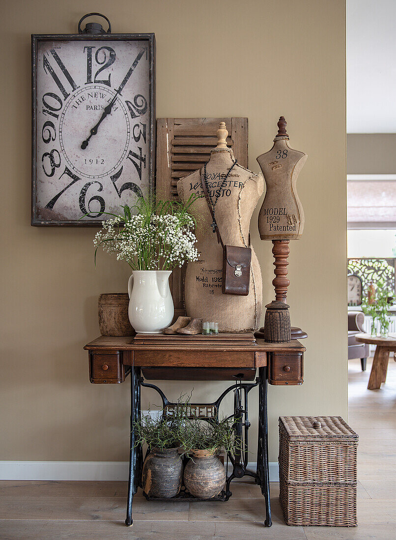 Antique sewing machine with table frame, dressmaker's dummies, vintage clock and bouquet of flowers in ceramic vase