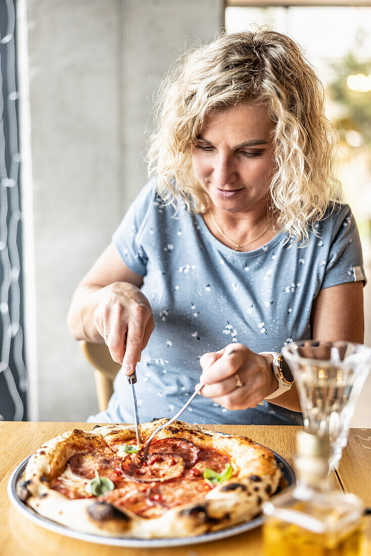 Frau isst Salamipizza