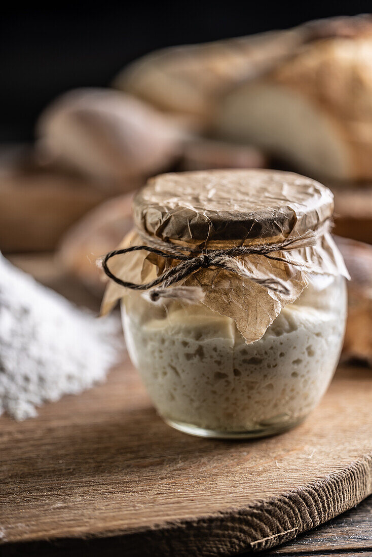 Matured rye sourdough in a jar with flour on a chopping board