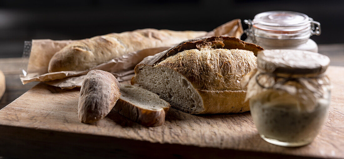 Rye sourdough in a jar and fresh bread on a chopping board