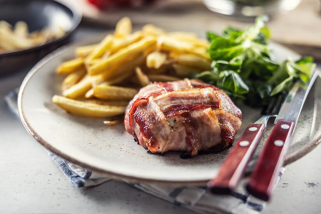 Gebratener Briekäse im Speckmantel mit Pommes Frites und Blattsalat