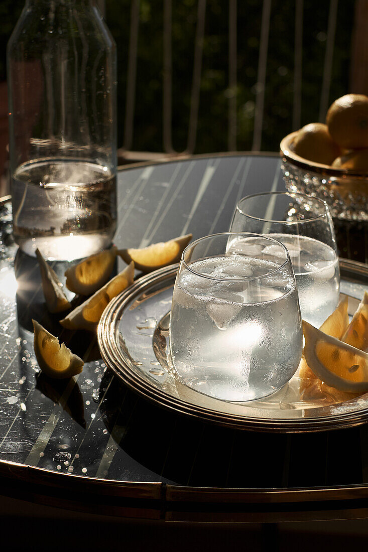 Soda mit Zitrone und Eiswürfeln auf einer Terrasse im Sonnenlicht