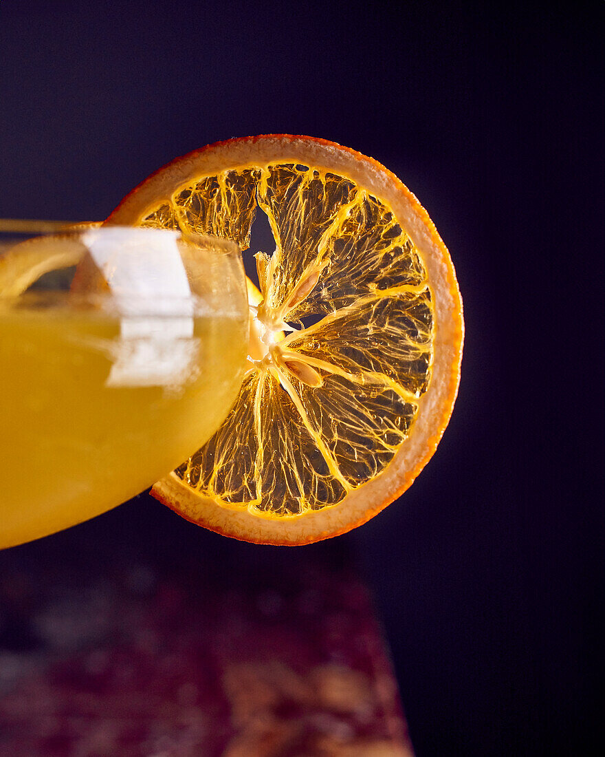 Orange-coloured cocktail with dried orange slice