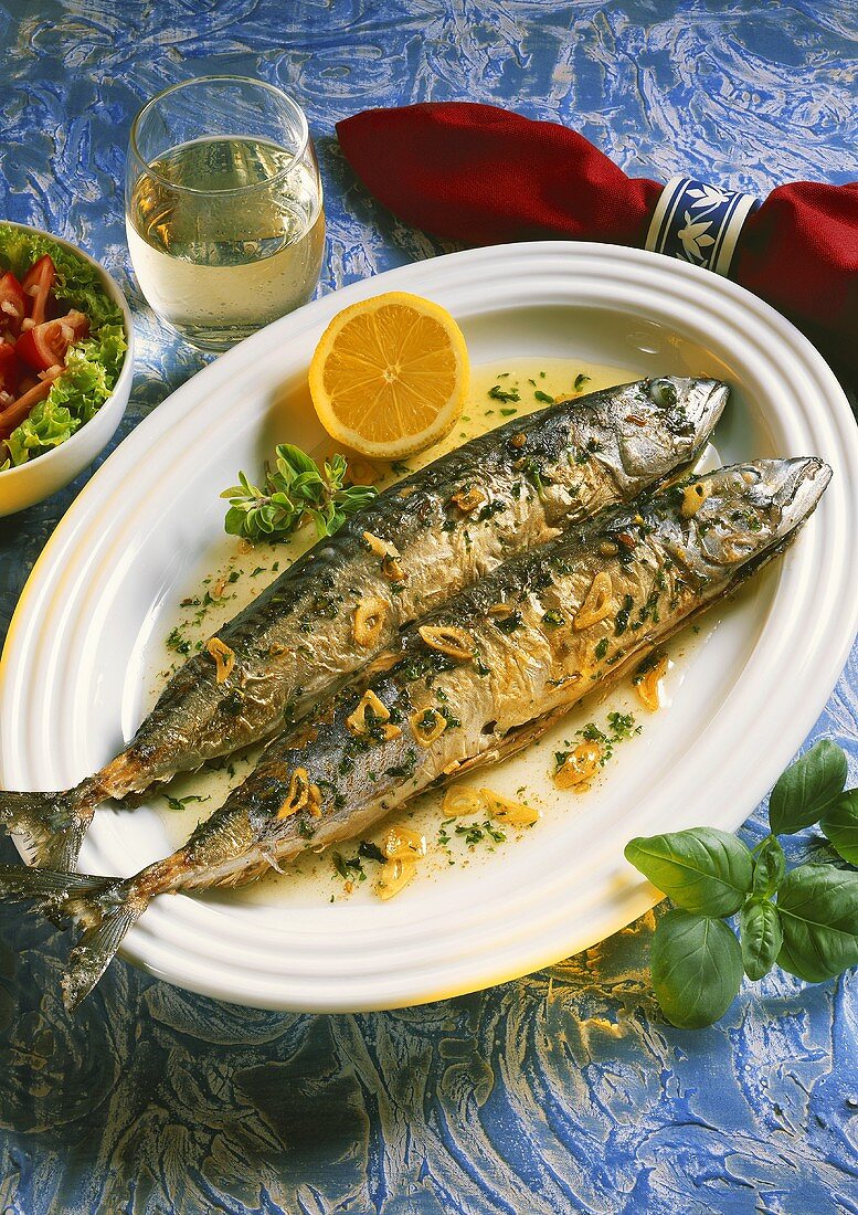 Garlic mackerel on white fish plate, decoration: wine glass