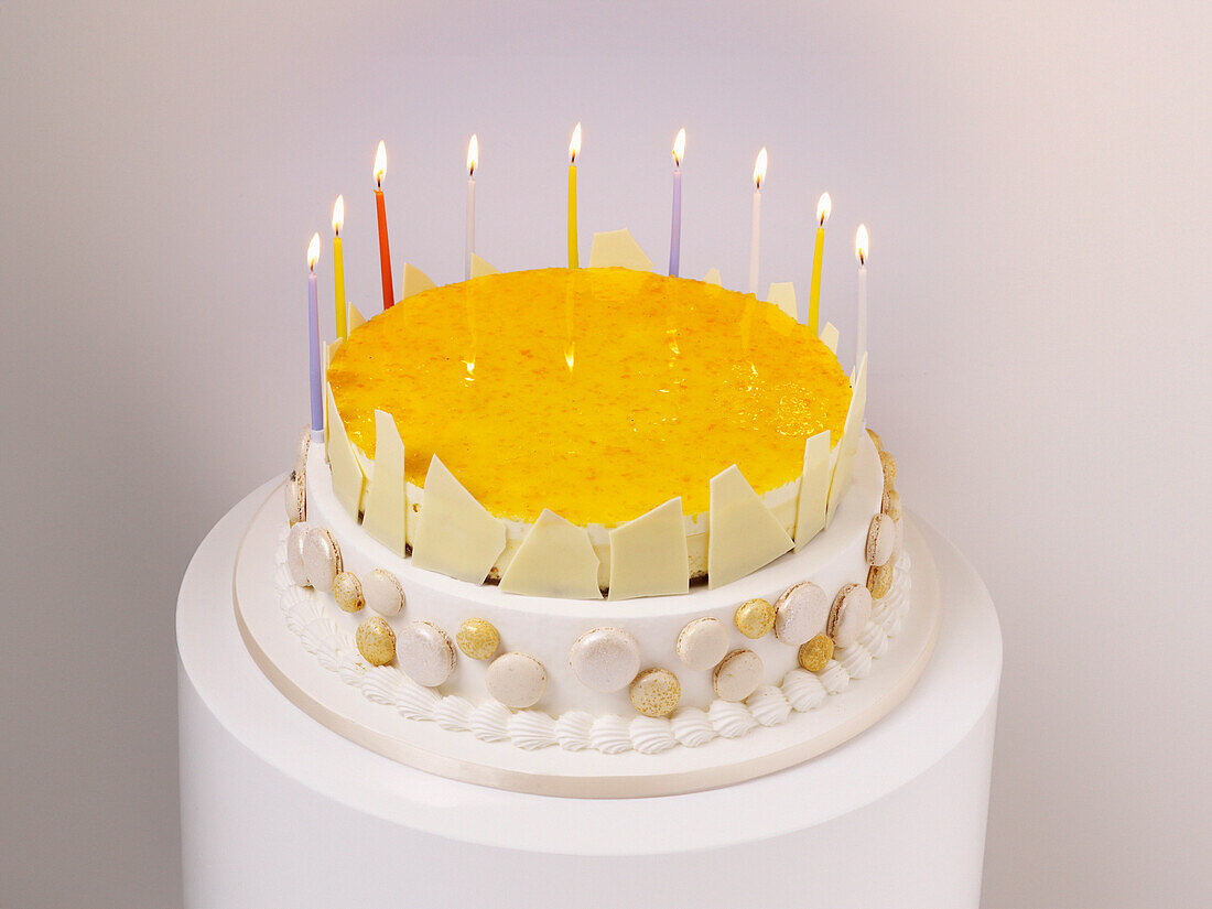 White birthday cake with fruit topping and candles