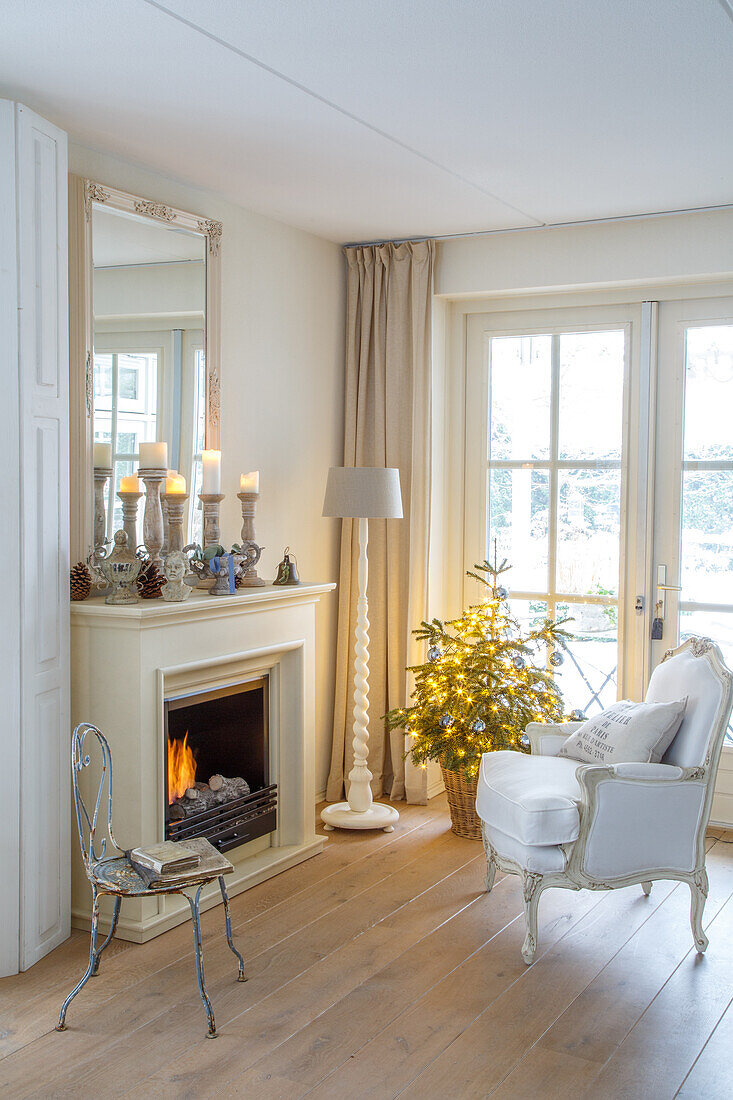 Cosy reading corner with armchair and fireplace next to a Christmas tree with Christmas decorations