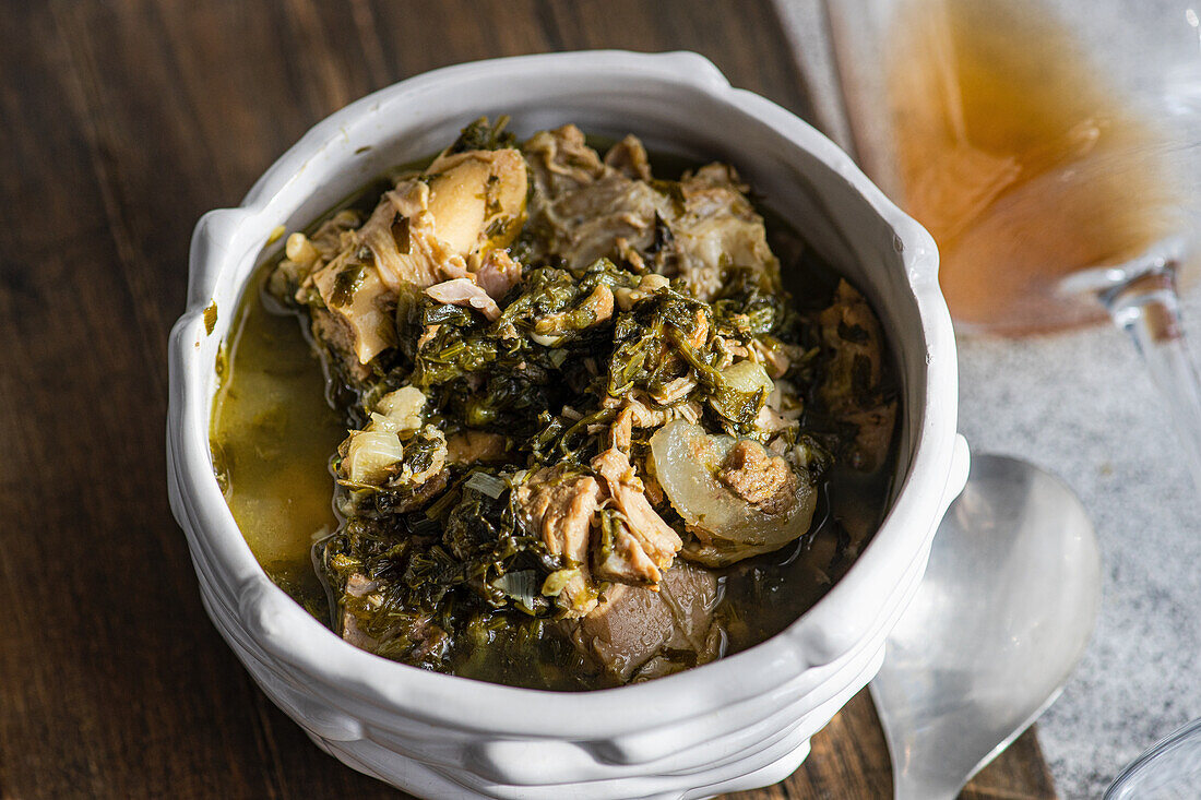 Traditional Georgian dish Chakapuli in a bowl and a glass of amber wine