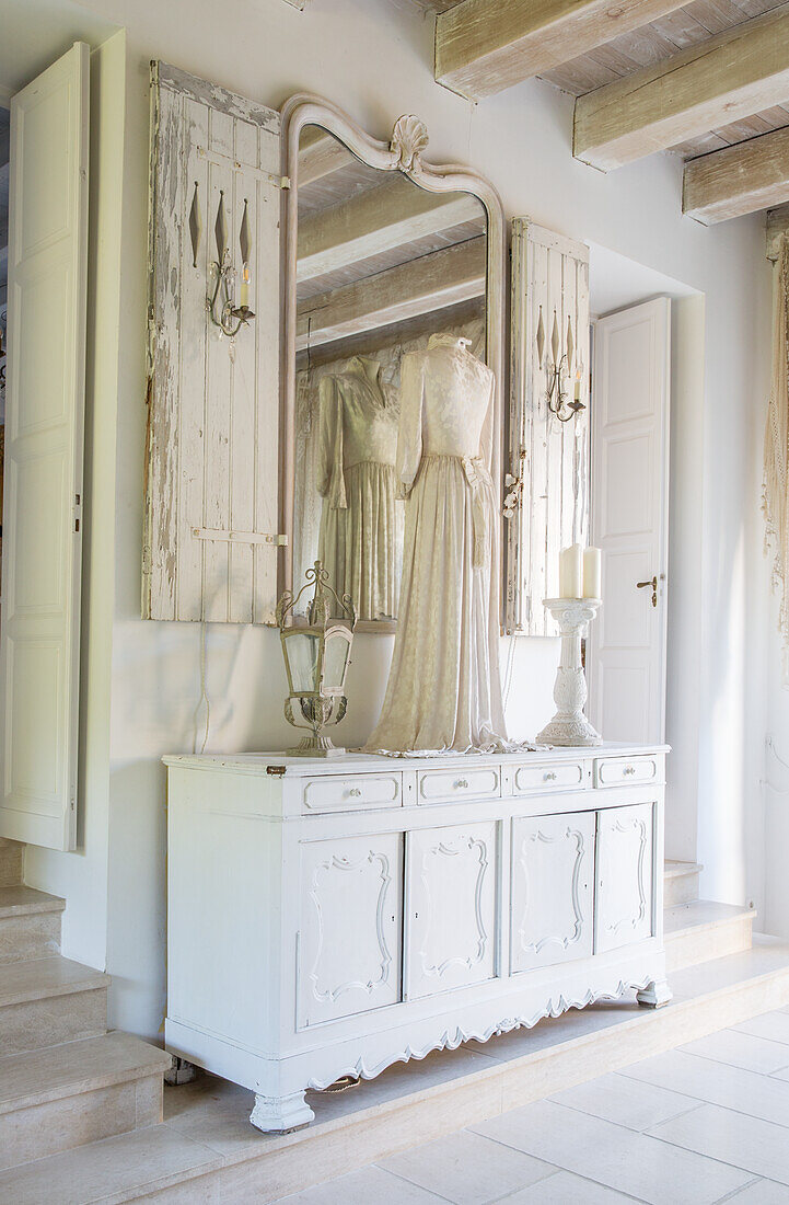 Shabby chic hallway with antique chest of drawers, mirror and dressmaker's dummy with white dress