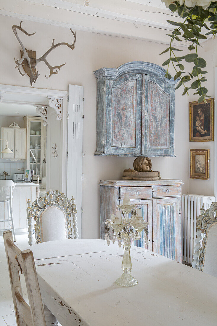 Shabby chic dining room with antique furniture and deer antlers on the wall