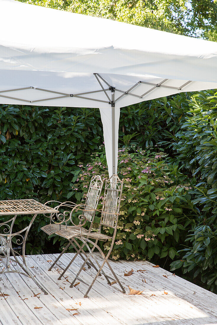 Pavillon mit Metallmöbeln auf Holzterrasse im Garten