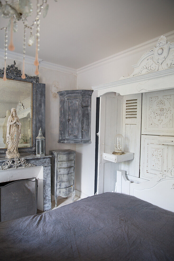 Baroque bedroom with antique furniture in grey tones and statue of the Virgin Mary on the mantelpiece