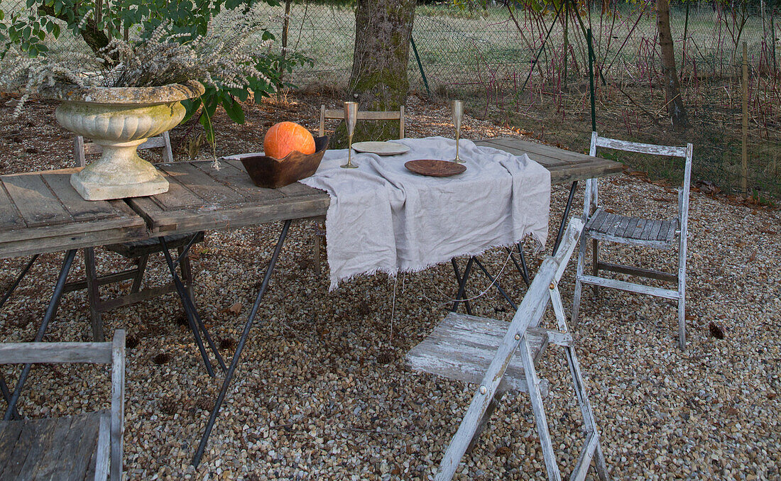 Rustikaler, gedeckter Gartentisch mit Kürbis und Leinentuch