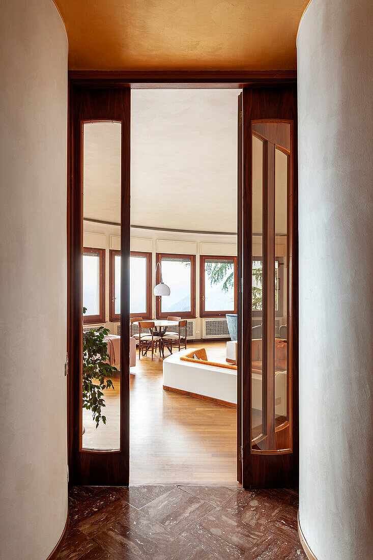 View through door to living room with many windows and wooden floor