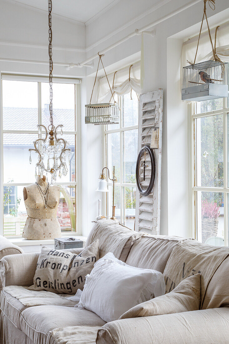 Bright living room with hanging birdcages, chandelier and dressmaker's dummy