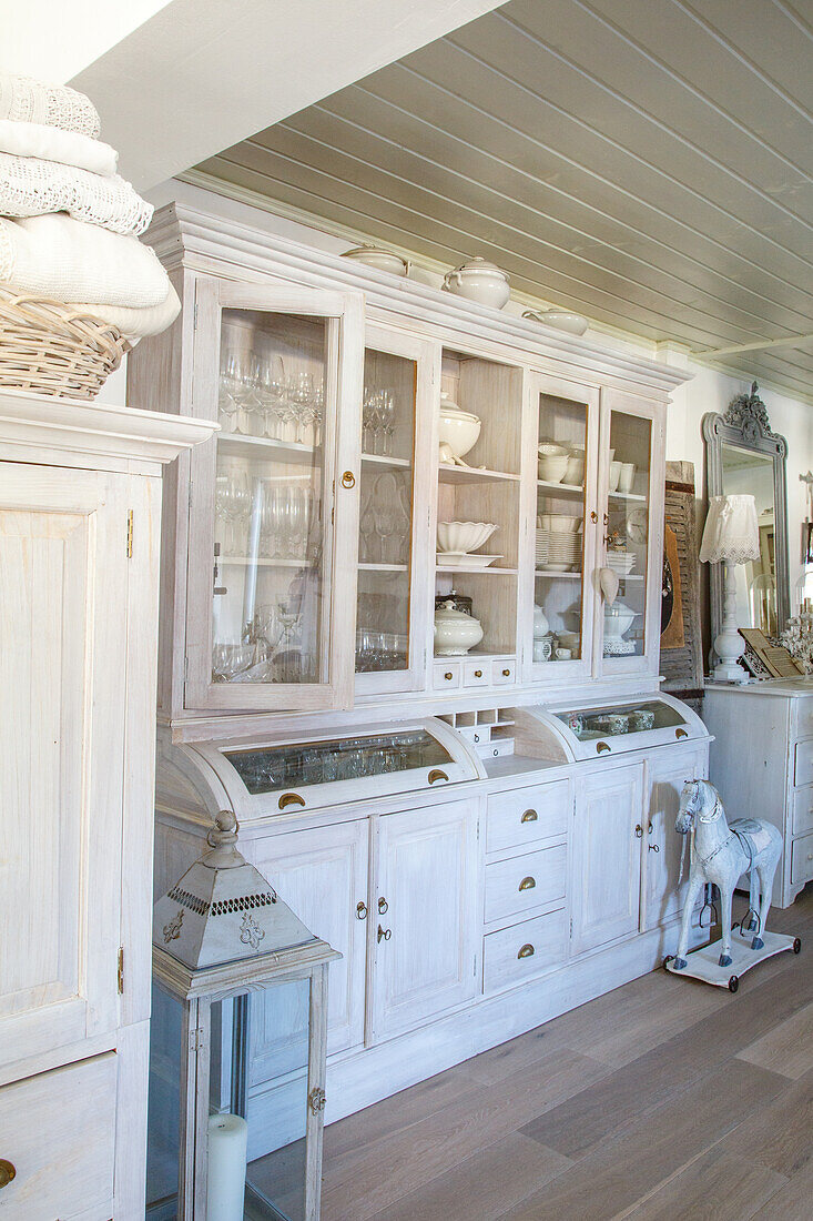 White country-style kitchen cabinet with glass doors and porcelain crockery