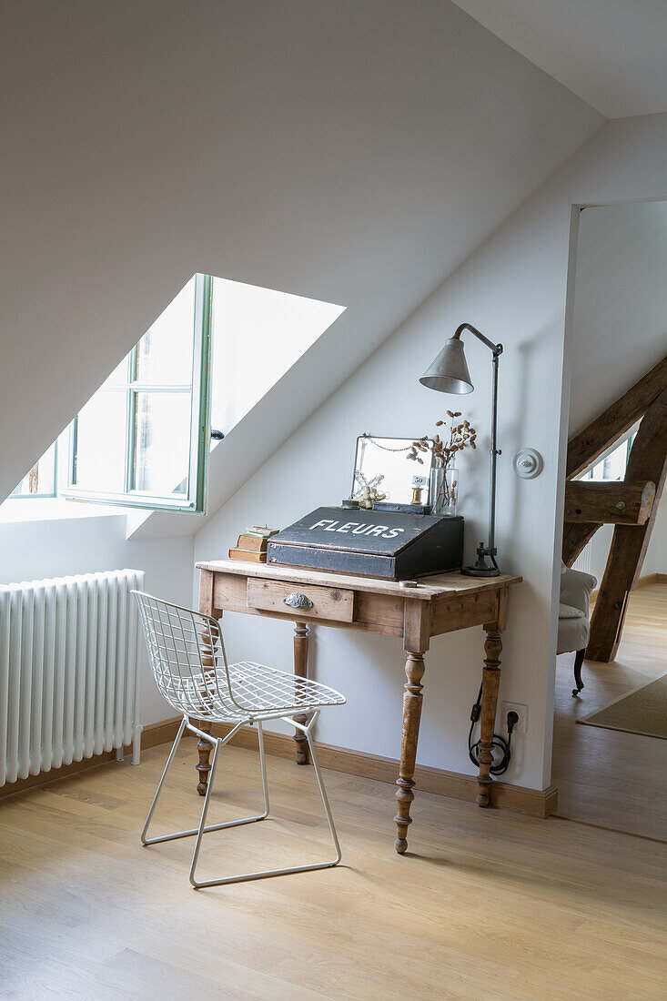 Antique wooden desk with metal chair in the attic area