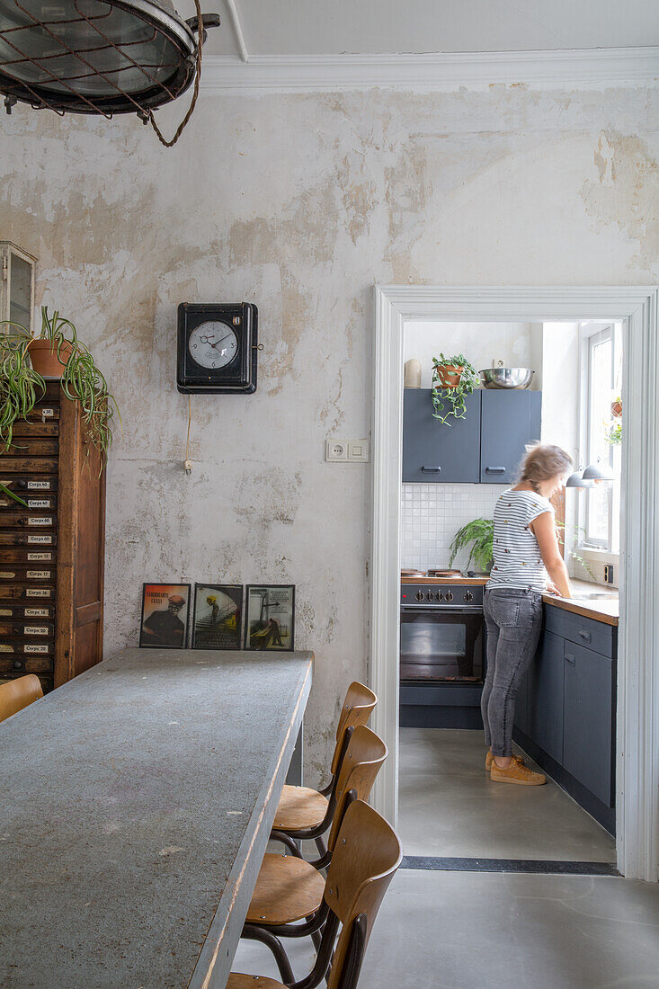 Dining area with vintage furniture, woman standing in kitchen