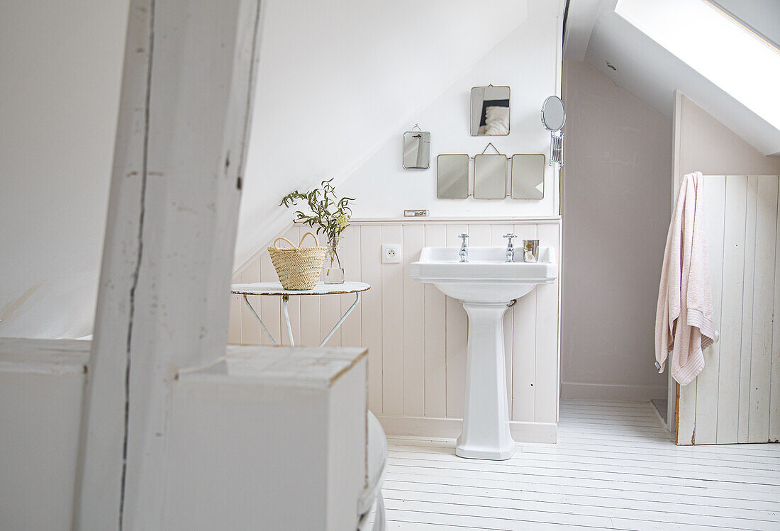 Bright bathroom with sloping ceiling and pillar washbasin