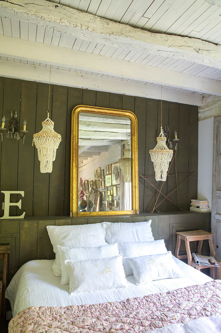 Bedroom with wooden panelling, golden mirror and crocheted lamps