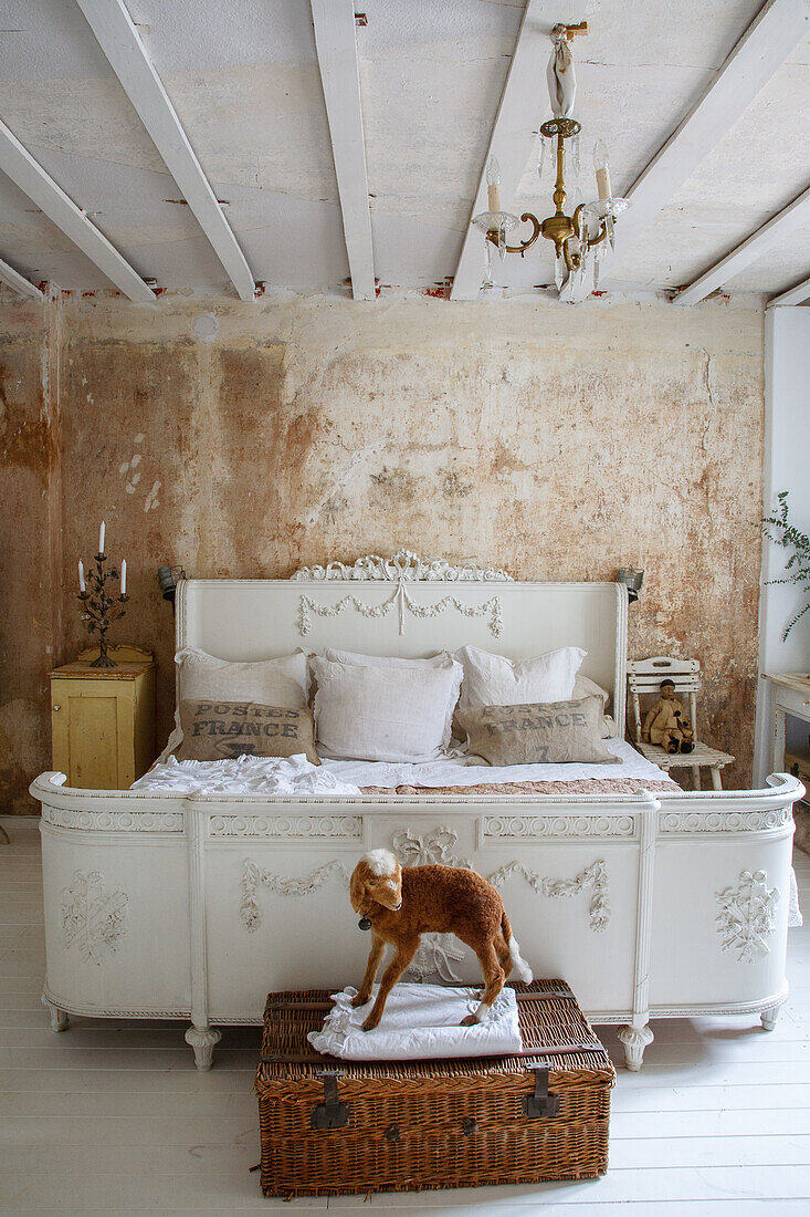 Rustic bedroom with patina wall, antique bed and chandelier