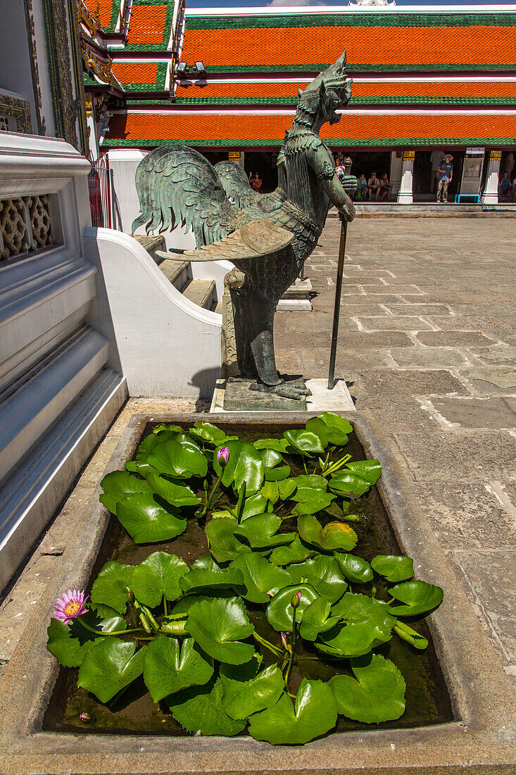 Bronzestatue eines mythischen Tantima-Vogels und blühende Seerosen im Grand Palace Komplex in Bangkok, Thailand