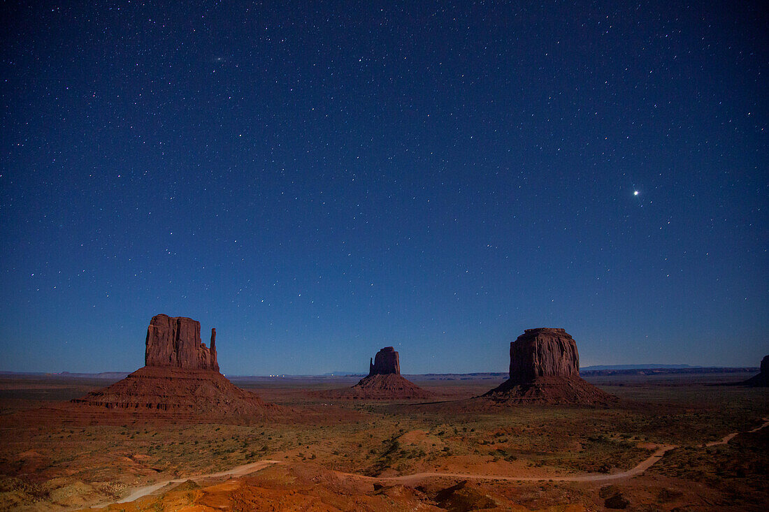 Stars over the moonlit Mittens and Merrick Butte in the Monument Valley Navajo Tribal Park in Arizona.
