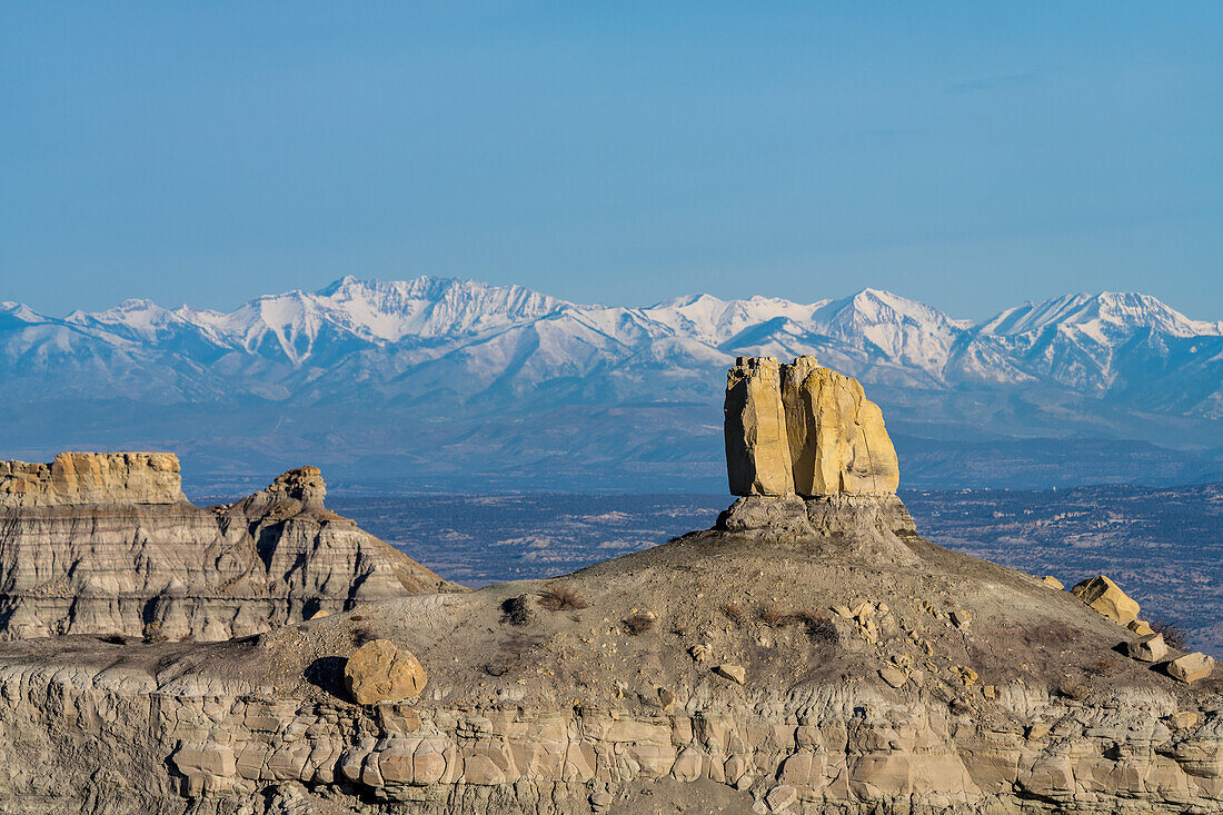 Angel Peak Scenic Area bei Bloomfield, New Mexico. Die Kutz Canyon Badlands mit den schneebedeckten San Juan Mountains im Hintergrund