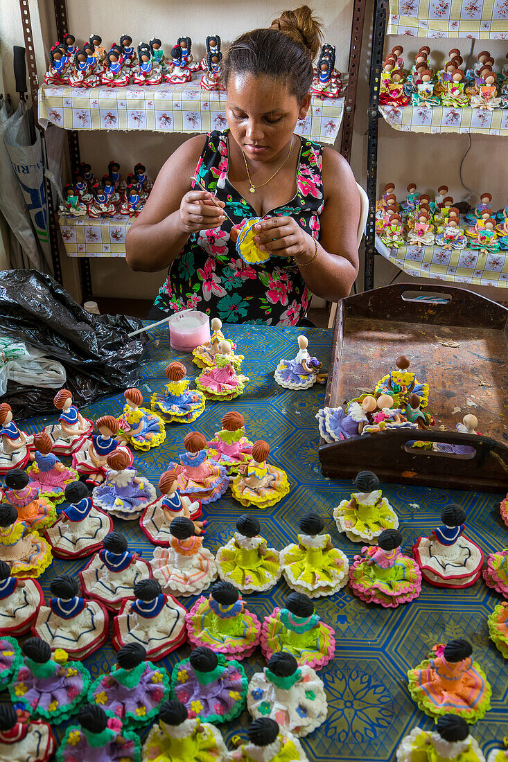 Ein Arbeiter schneidet das Haar einer dominikanischen gesichtslosen Puppe in einer Heimwerkstatt in der Dominikanischen Republik. Die gesichtslosen Puppen repräsentieren die ethnische Vielfalt der Dominikanischen Republik