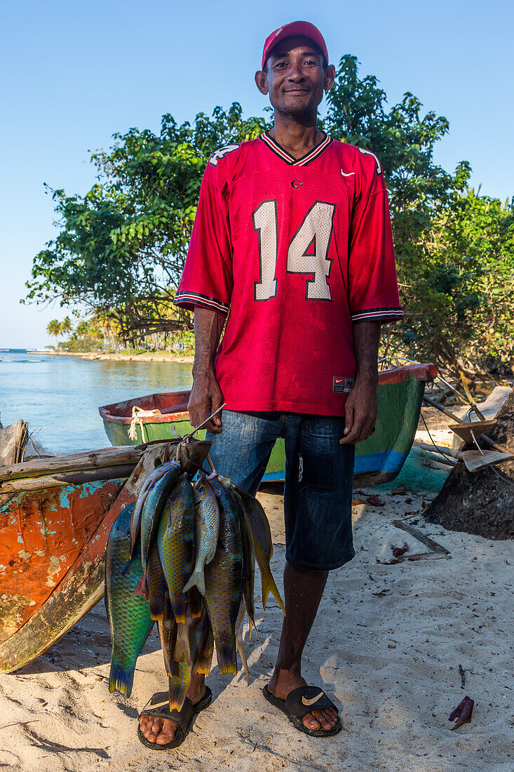 Ein dominikanischer Fischer mit seinem Fang am Strand von Bahia de Las Galeras auf der Halbinsel Samana, Dominikanische Republik