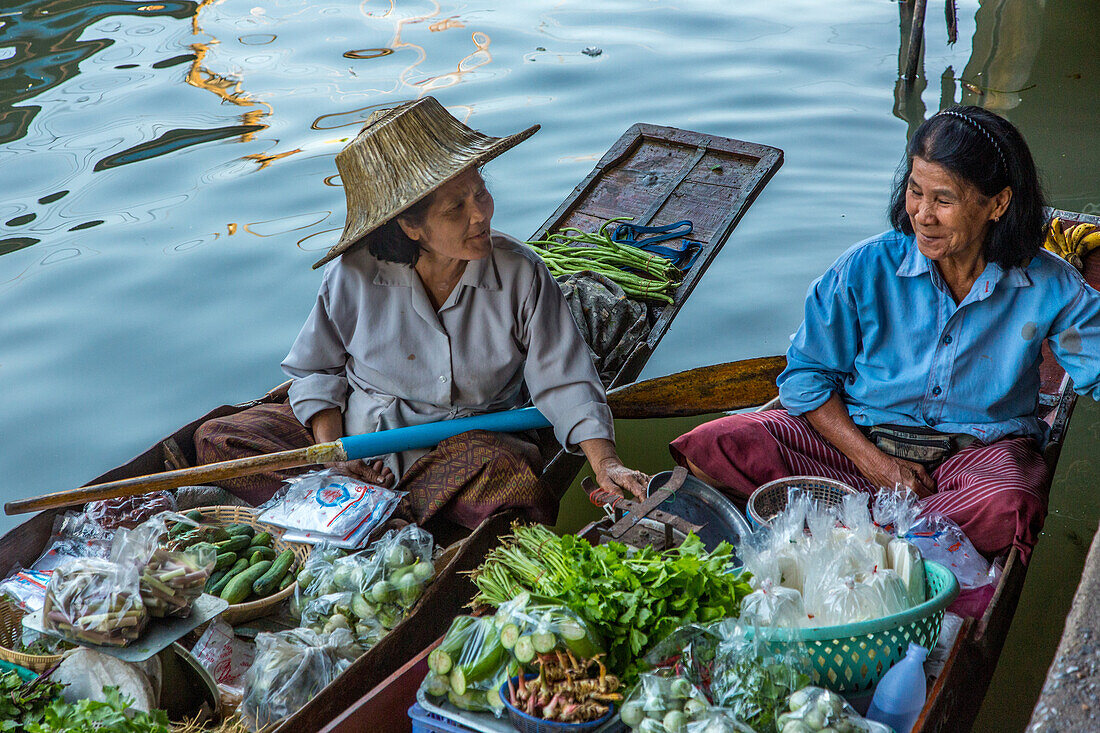 Social interaction between Thai vendors on their boats in the Damnoen Saduak Floating Market in Thailand.