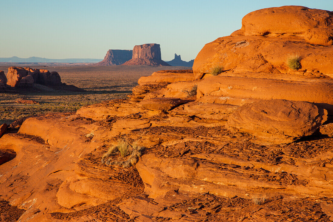 Farbenfroher erodierter Sandstein bei Sonnenuntergang im Mystery Valley im Monument Valley Navajo Tribal Park in Arizona. Die Monumente von Utah liegen dahinter.