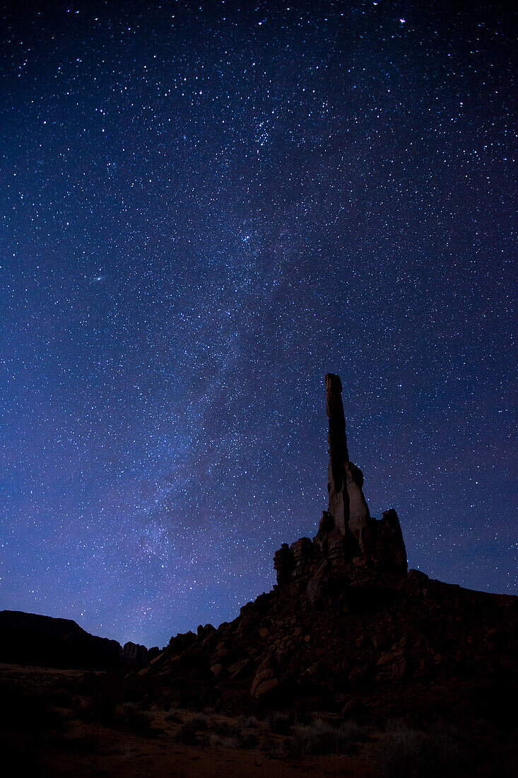 The Milky Way over the moonlit Totem Pole at night in the Monument Valley Navajo Tribal Park in Arizona.