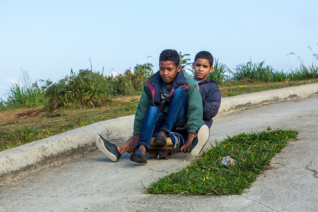 Dominican boys ride their homemade skateboard near Constanza in the Dominican Republic.