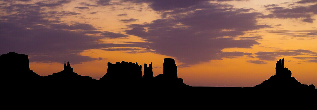 Sonnenaufgangssilhouette der Utah-Monumente im Monument Valley Navajo Tribal Park in Arizona. L-R: Brighams Grab, König auf seinem Thron, die Postkutsche, der Bär und das Kaninchen, Castle Butte und der große Indianerhäuptling. Sie werden oft als Utah-Monumente bezeichnet, weil sie direkt hinter der Grenze in Utah liegen, während der größte Teil des Parks in Arizona liegt.