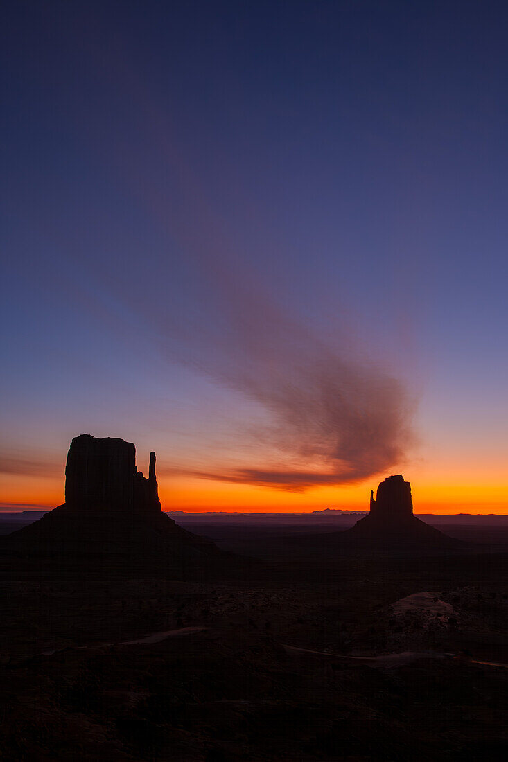 Curved cloud over the Mittens before sunrise in the Monument Valley Navajo Tribal Park in Arizona.