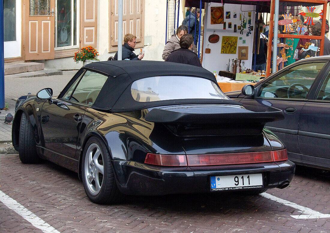 An expensive Porsche convertible sports car parked on the street in the historic Old Town of Vilnius, Lithuania. A UNESCO World Heritage Site.