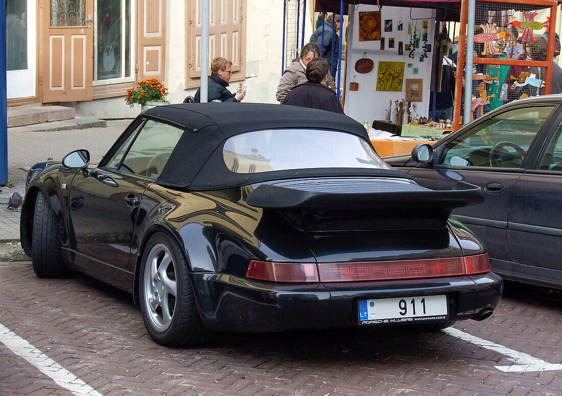Ein teurer Porsche Cabrio-Sportwagen parkt auf der Straße in der historischen Altstadt von Vilnius, Litauen. Eine Stätte des UNESCO-Weltkulturerbes