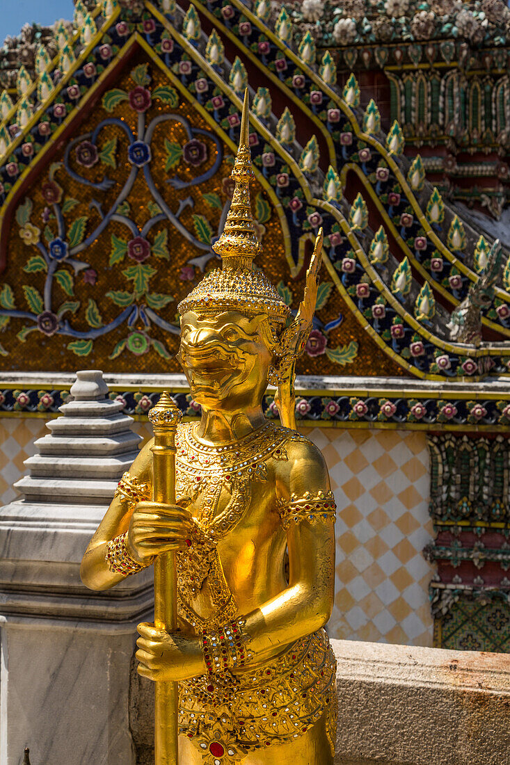 Golden statue of a Singhaphanon mythical creature guards the Phra Wiharn Yod in the Grand Palace complex in Bangkok, Thailand. A Singhaphanon has the upper body of a monkey and lower body of a lion.