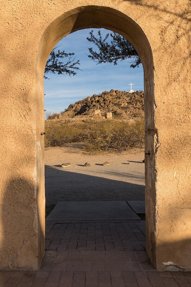 Ein gewölbter Durchgang durch die Schutzmauer der Mission San Xavier del Bac umrahmt den Grotto Hill, Tucson Arizona