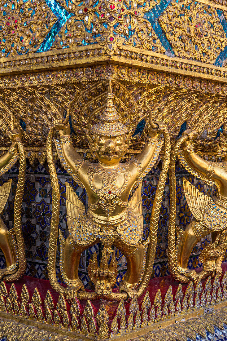 Golden statues of Garuda vs. the naga guards the Temple of the Emerald Buddha in the Grand Palace complex in Bangkok, Thailand.